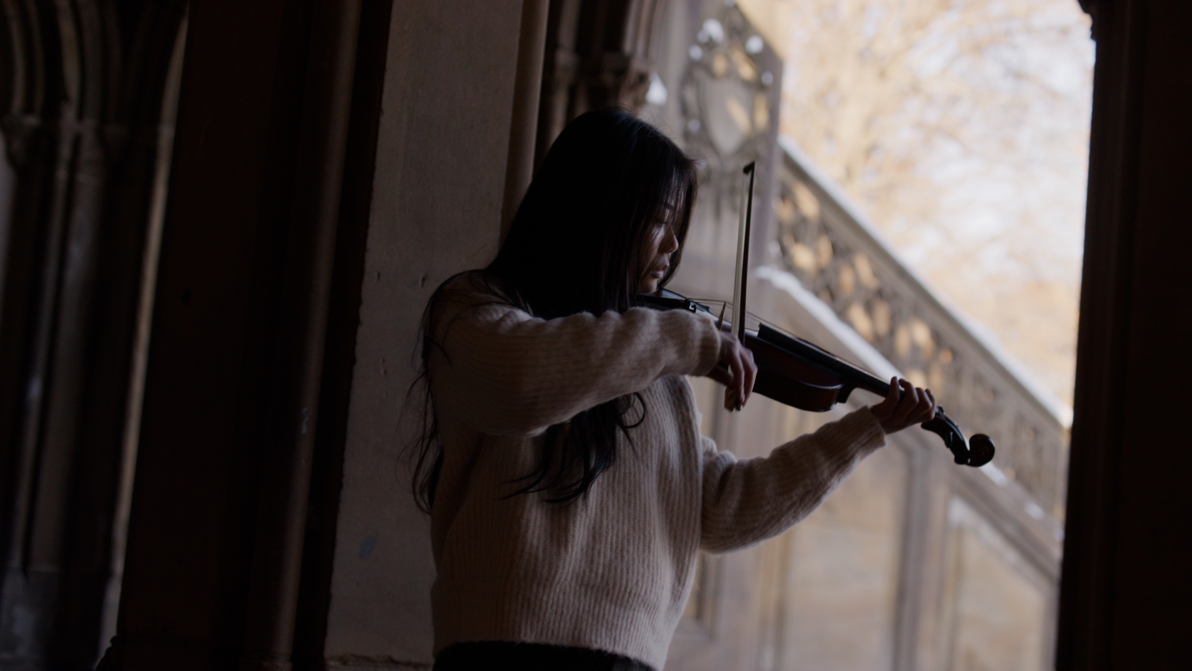 Concerto film still with violinist in interior shadow